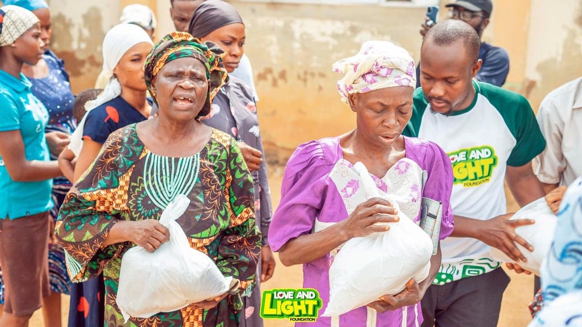 Women carrying bags of food staples received at a Love & Light Foundation community outreach