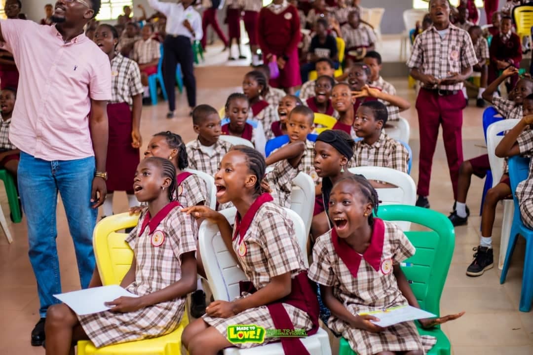 Secondary school students in uniform cheering during a Love & Light Foundation school outreach