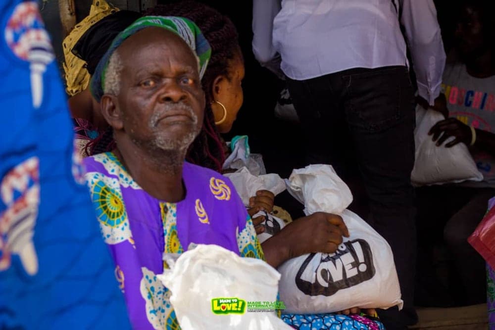 An elderly man holding a relief bag received at a Love & Light Foundation food outreach