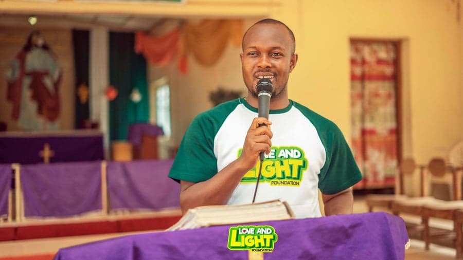 Oluninyo Ademola-Idowu Esq, Founder / Executive Director of Love & Light Foundation, speaking into a microphone in a foundation T-shirt