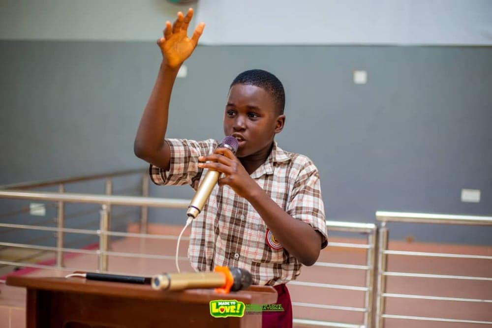 A school pupil in uniform speaking into a microphone at a school outreach